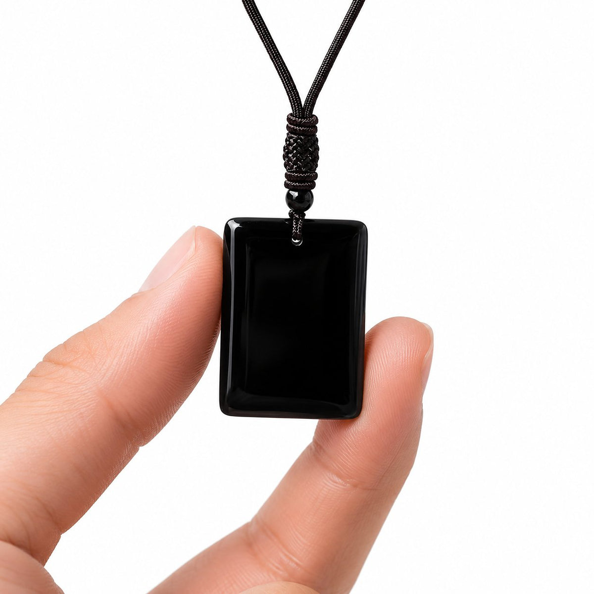 Hand holding a black obsidian pendant