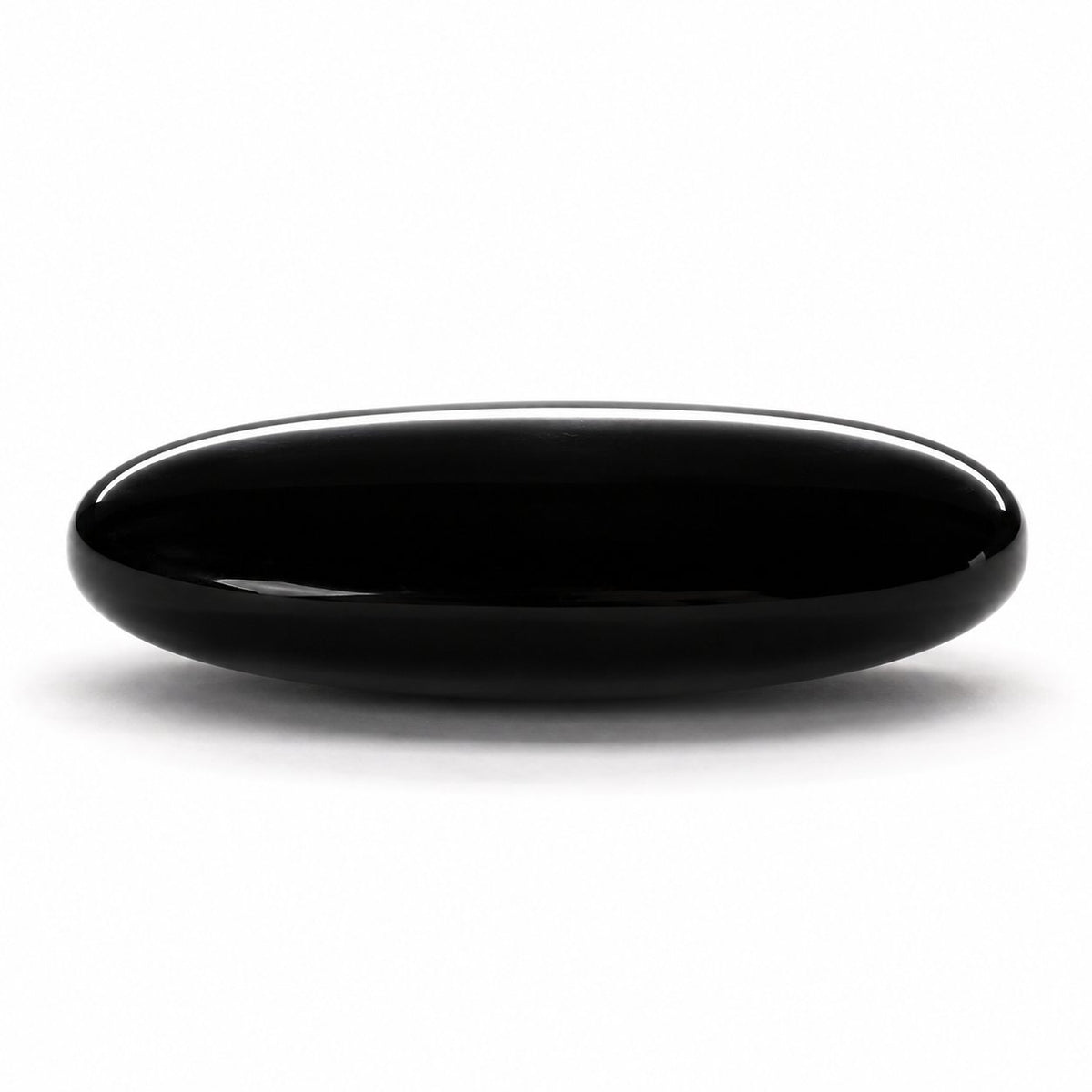 Side profile of black obsidian palm stone showing thickness